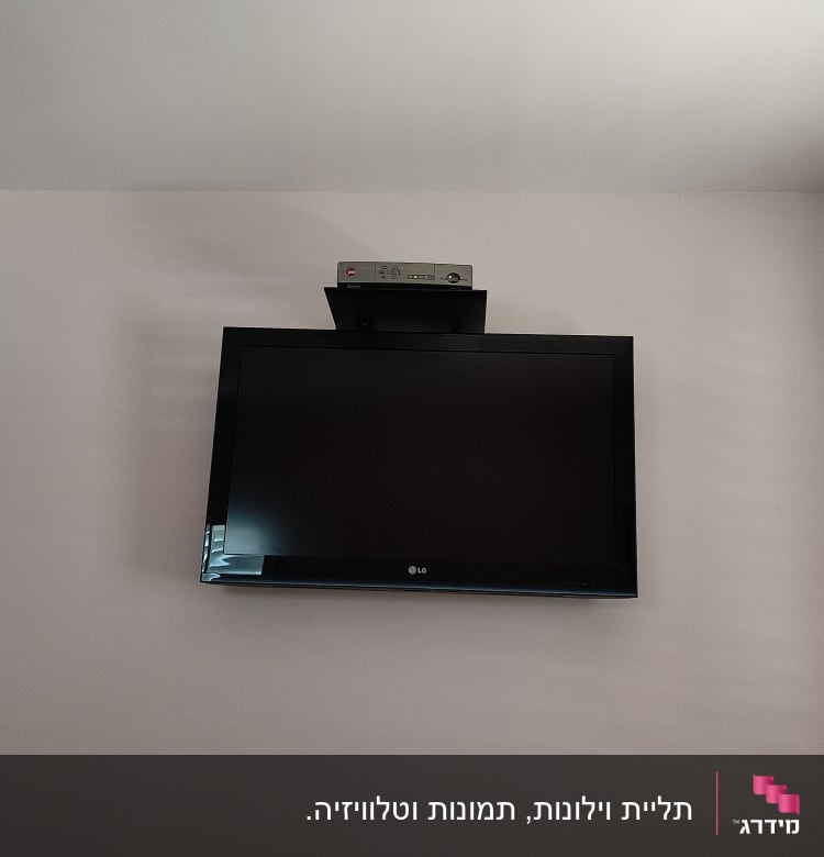 טלוויזיה תלויה על הקיר עם ממיר על מדף